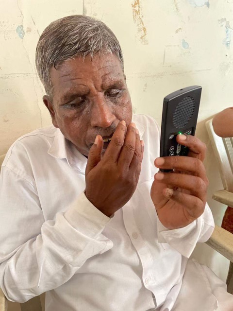 Blind man with MegaVoice Blind man listening to his MegaVoice audio Bible